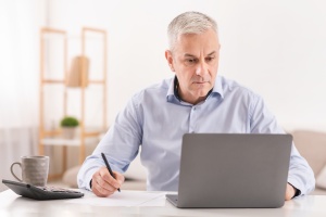 man taking notes in meeting at home