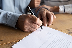 a senior couple signing a document for a life insurance policy that will provide estate protection