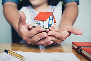 woman and child holding small house figurine