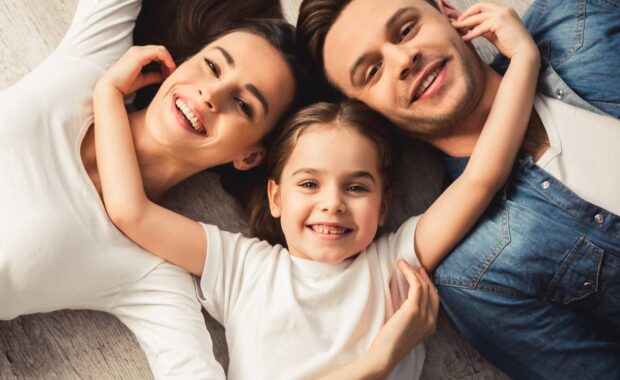 Family smiling while girl having her hand on neck line of other two