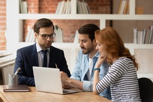 Insurance agent showing policy information to a couple in his laptop