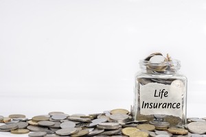 Life insurance written glass jar surrounded by coins as well as filled with them