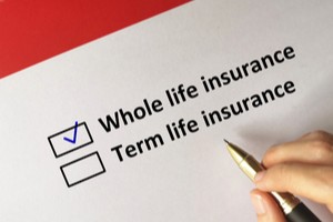 Whole life insurance term life insurance written on paper while hand ticking former option