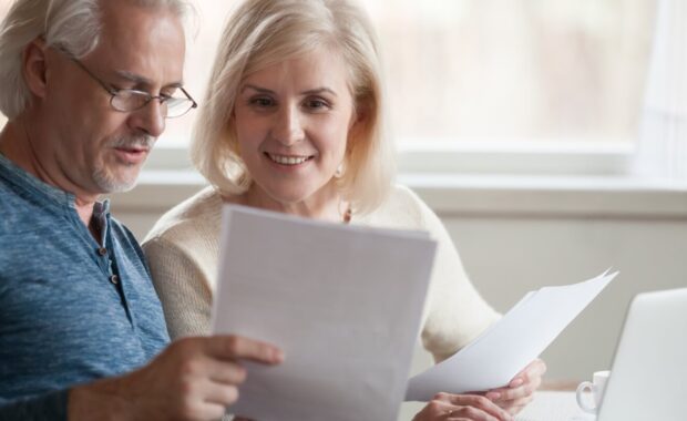 old middle aged couple holding reading good news in document
